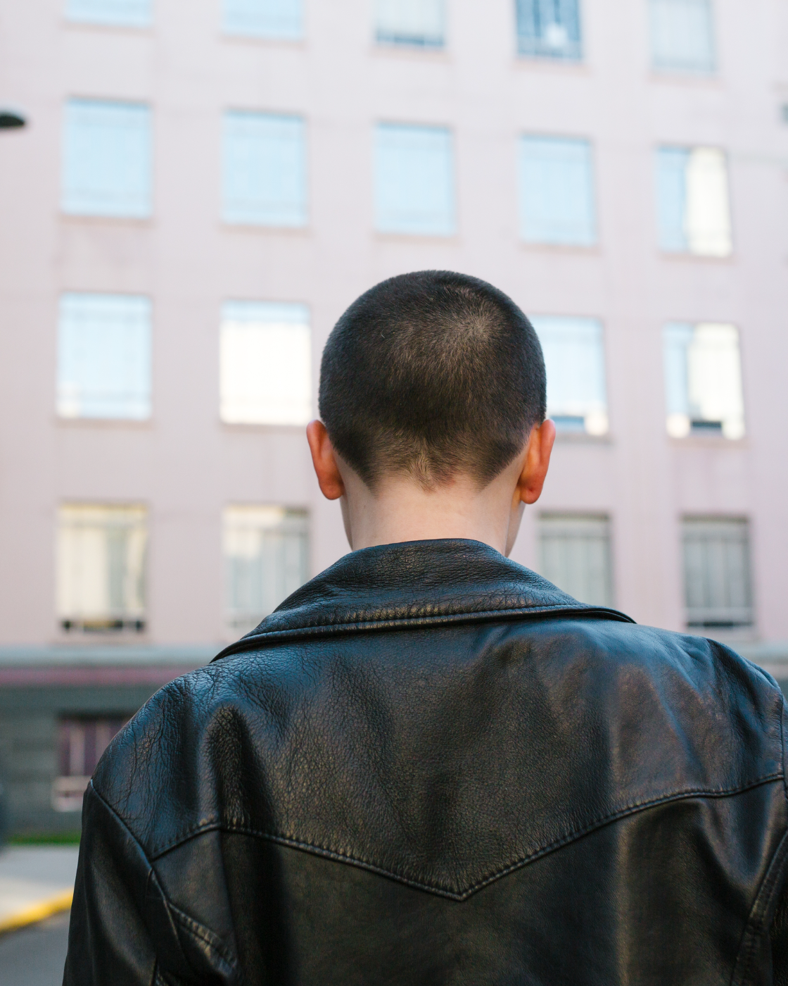 A young person seen from behind, facing a large building